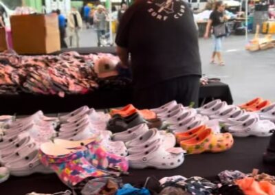 Person surrounded by stolen items including shoes and clothing displayed at an outdoor market